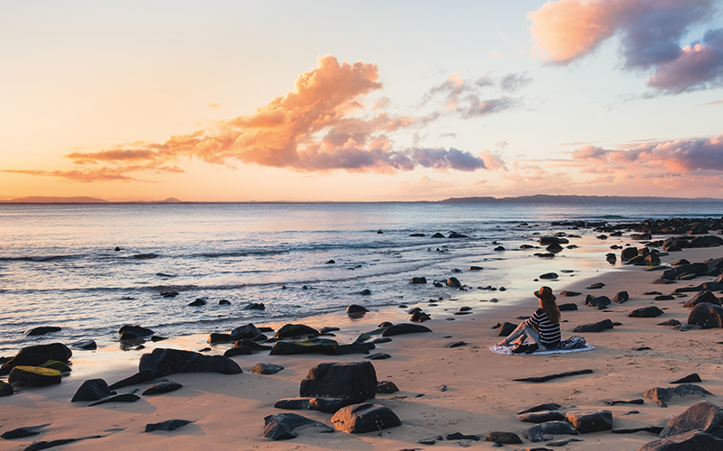 Woman set on the beach looking at the water