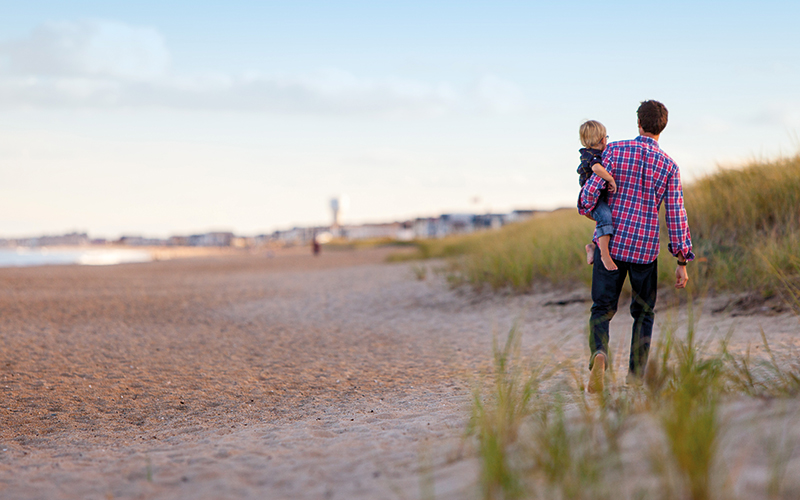 Father and son walking on the sand