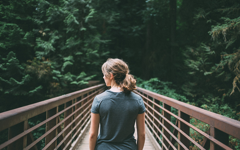 Woman looking out on a bridge in the forest