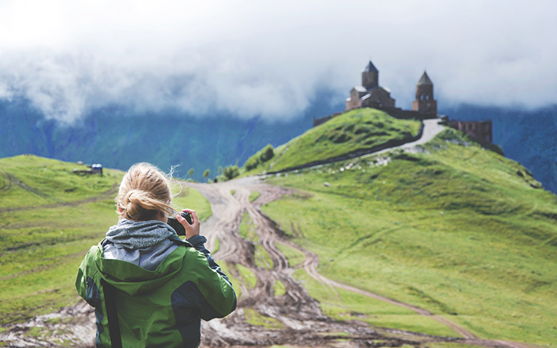 Woman taking a photo of castle on the hill