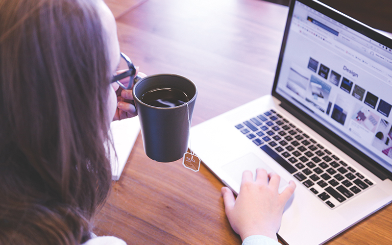 Woman drinking coffee browsing on laptop