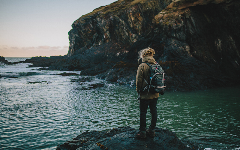 Woman standing on rock looking at water