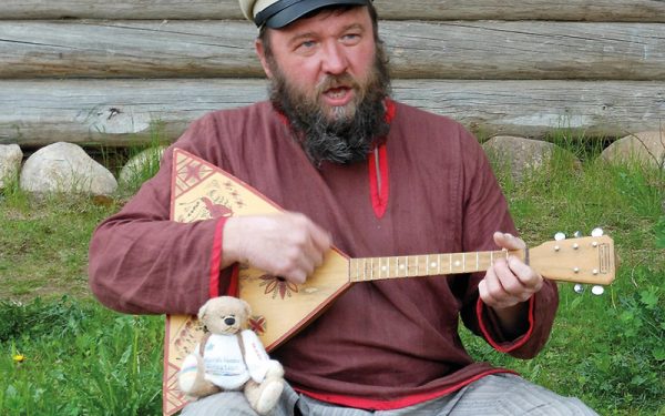 Man playing guitar with Rainbow Bear