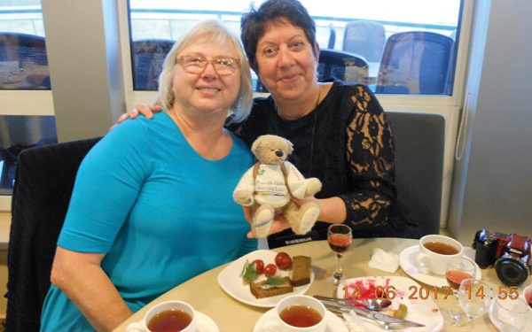 Two ladies posing with Rainbow Bear