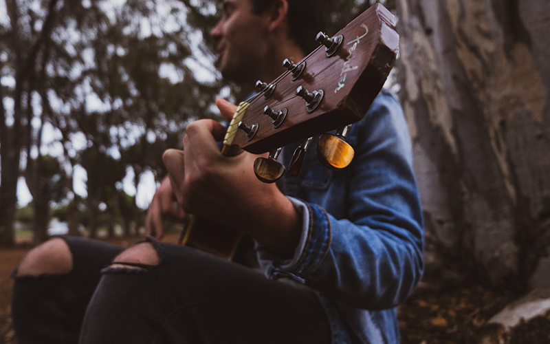 Person playing guitar in the woods