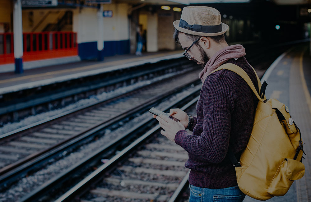 Man looking at phone on train platform