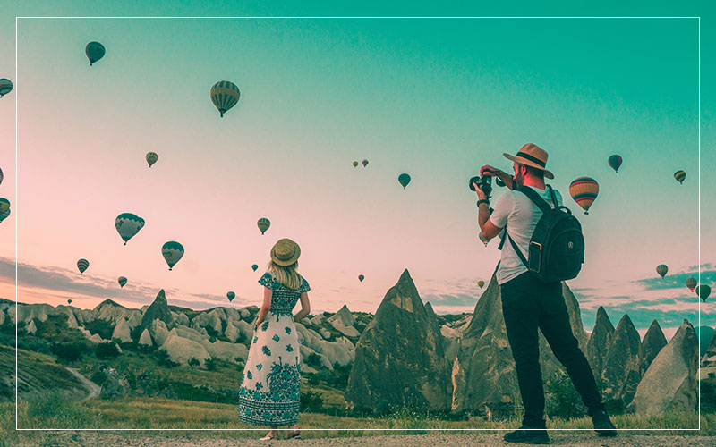 Man taking photo of woman looking at hot air balloons