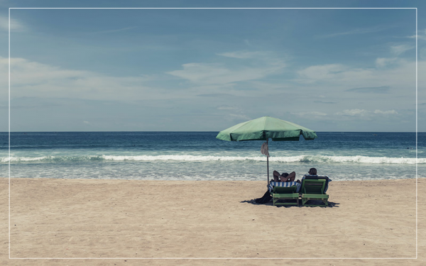 two people sat on sun lounger on the beach